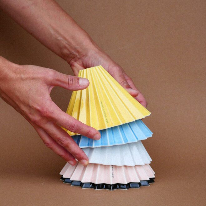 Origami Dripper in allen Farben aufeinander gestapelt, von Person drapiert