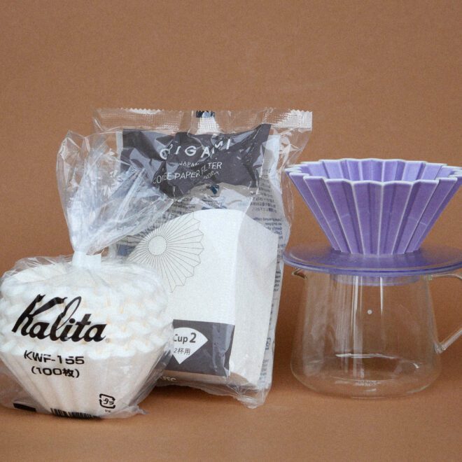 Kaffee Glaskanne mit Origami Filterhalter in purple, links davon Origami und Kalita Wave Filterpapier