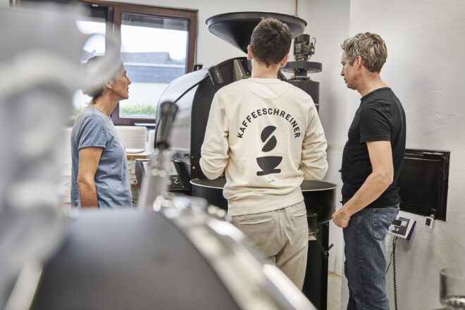 Kaffeeschreiner mit Kunden vor Kaffeeröster