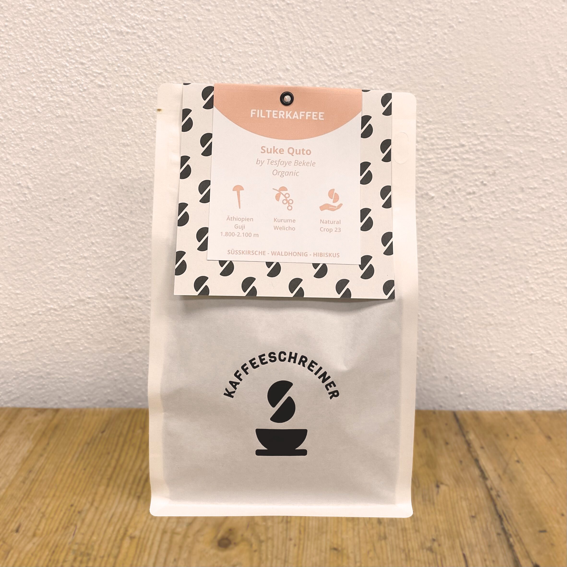 Weiße Kaffeeverpackung mit Kaffeeschreiner Logo von Suke Quto Natural