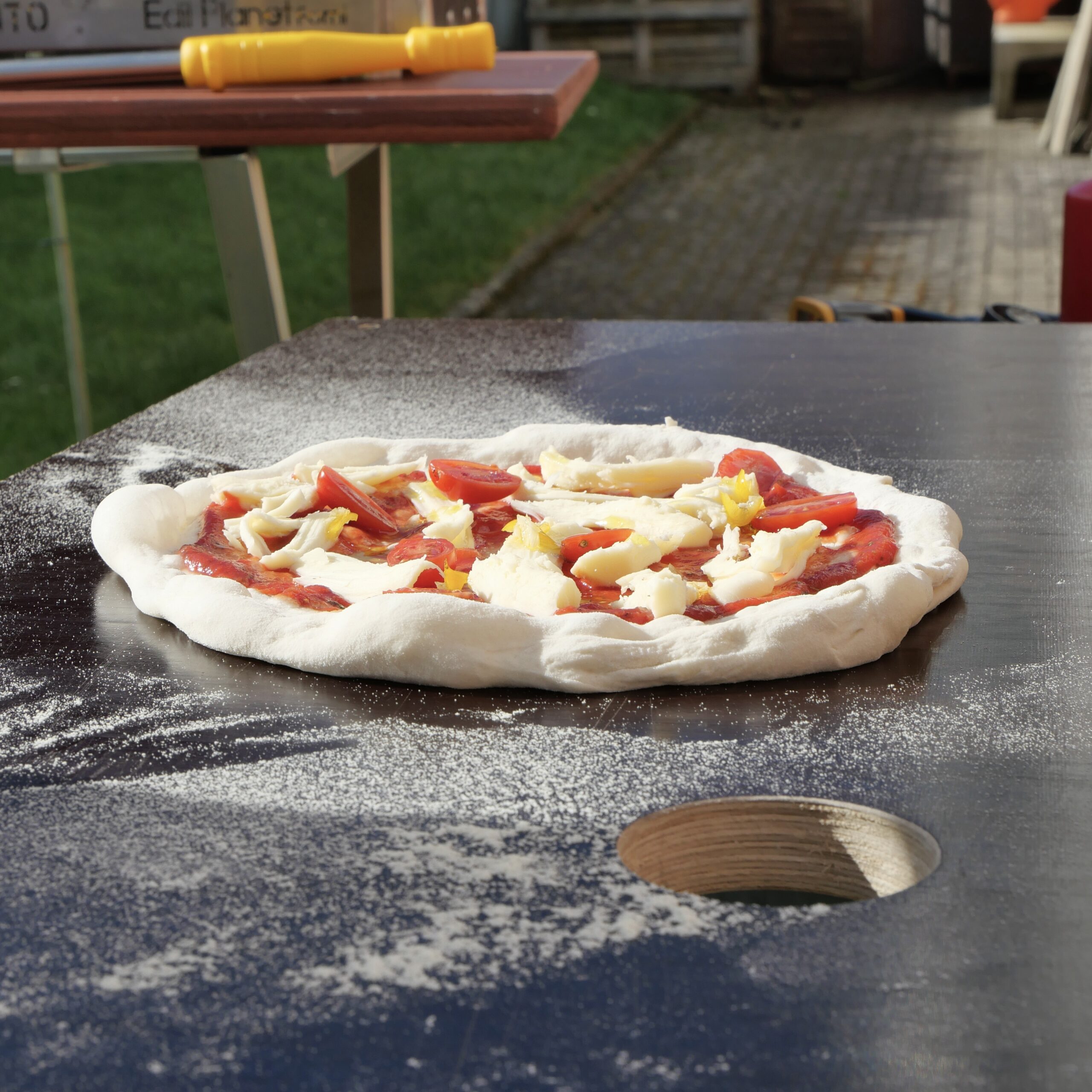 Rohe Pizza auf Tisch bevor sie in den Ofen geschoben wird